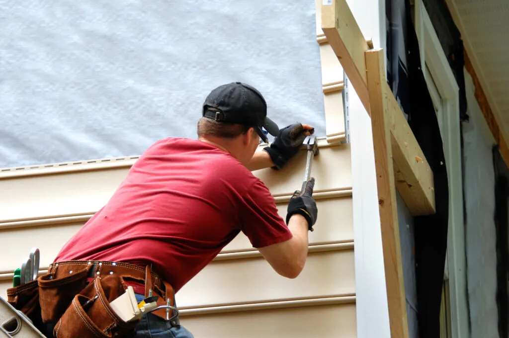 Homeowner installs vinyl siding using a hammer
