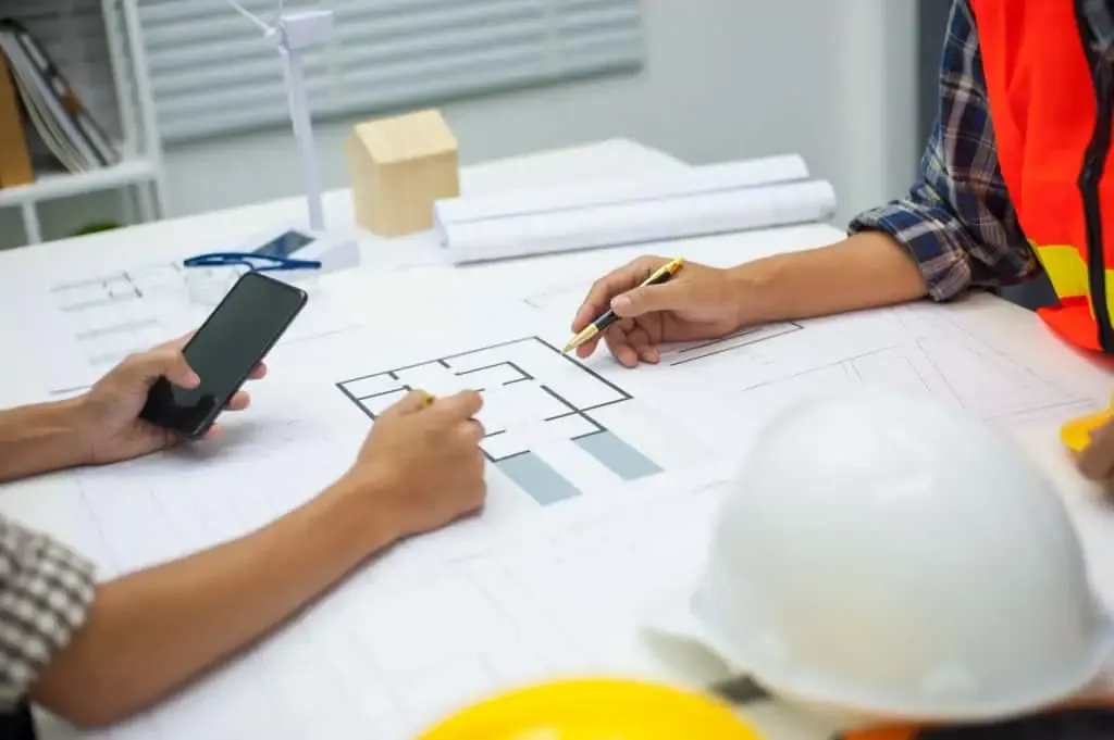 Homeowner consulting with contractor over blueprints